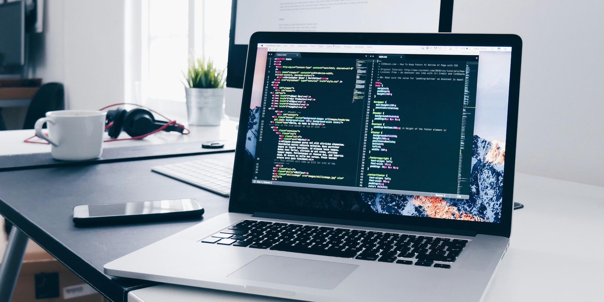 Cover image for this post: Open Macbook with code on the screen, sitting on a relatively minimal desk with a coffee cup beside it.