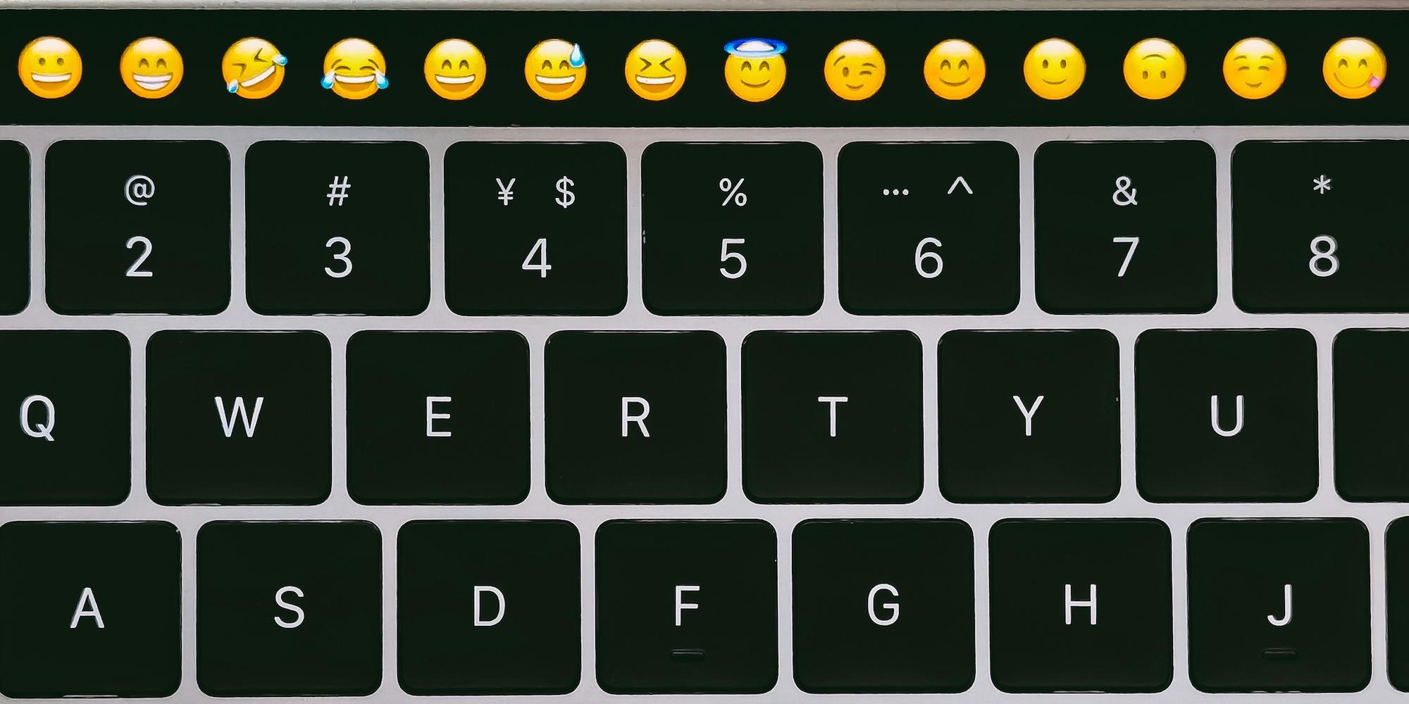Cover image for this post: A close up of a Mac keyboard with the upper control bar showing emoji faces.